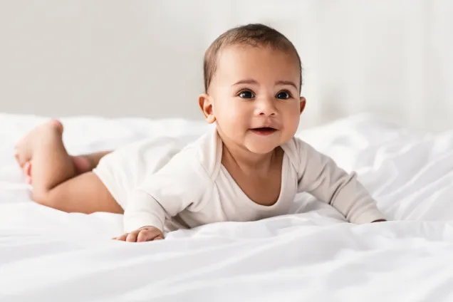Barn som ligger på mage och tittar fram. Bild.